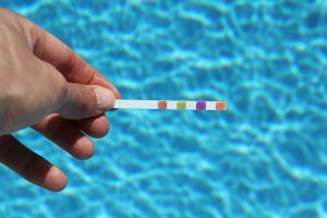 Man Holding PH Level Tester by Pool